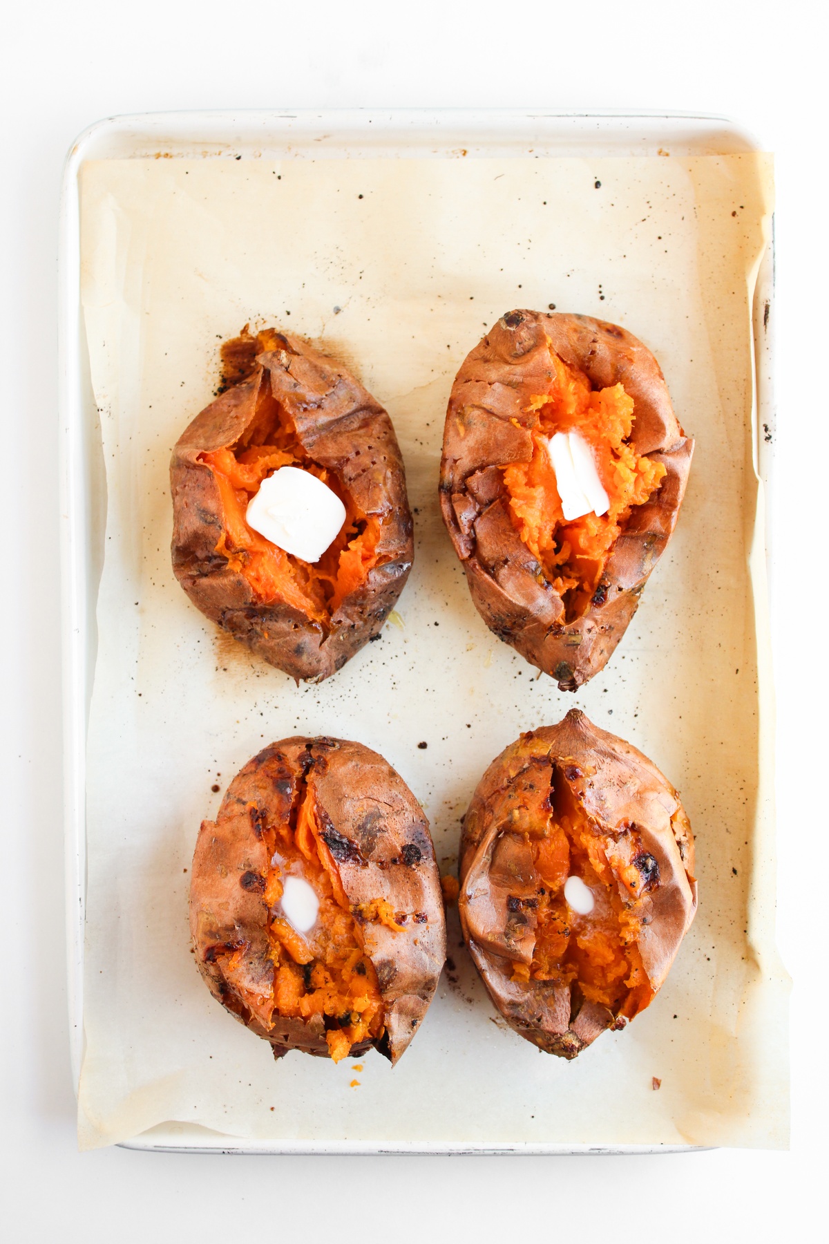 Cooked sweet potatoes with pads of butter in the middles.