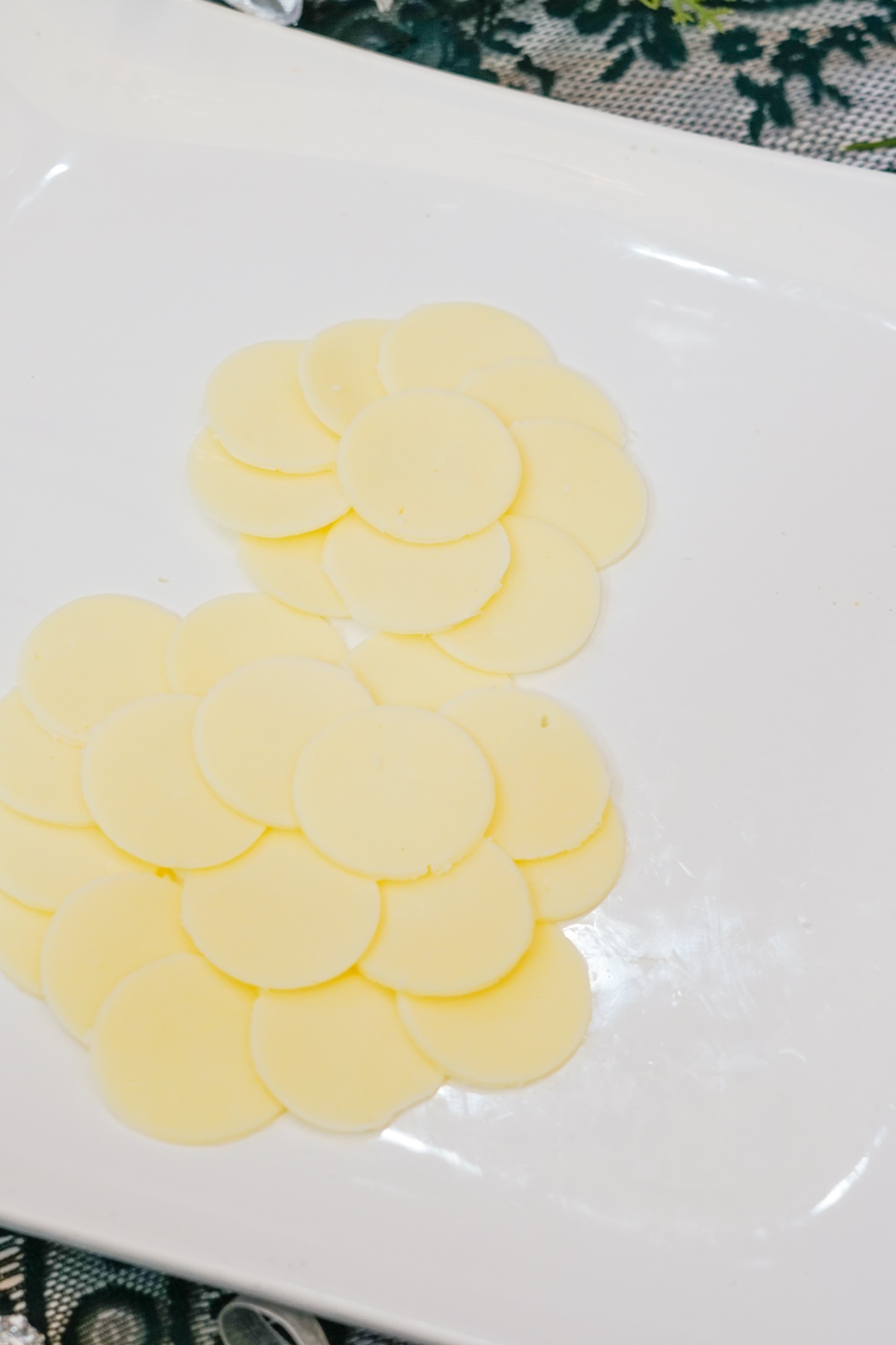 Overlapping round white cheese slices arranged in two connected circular clusters on a white rectangular plate.