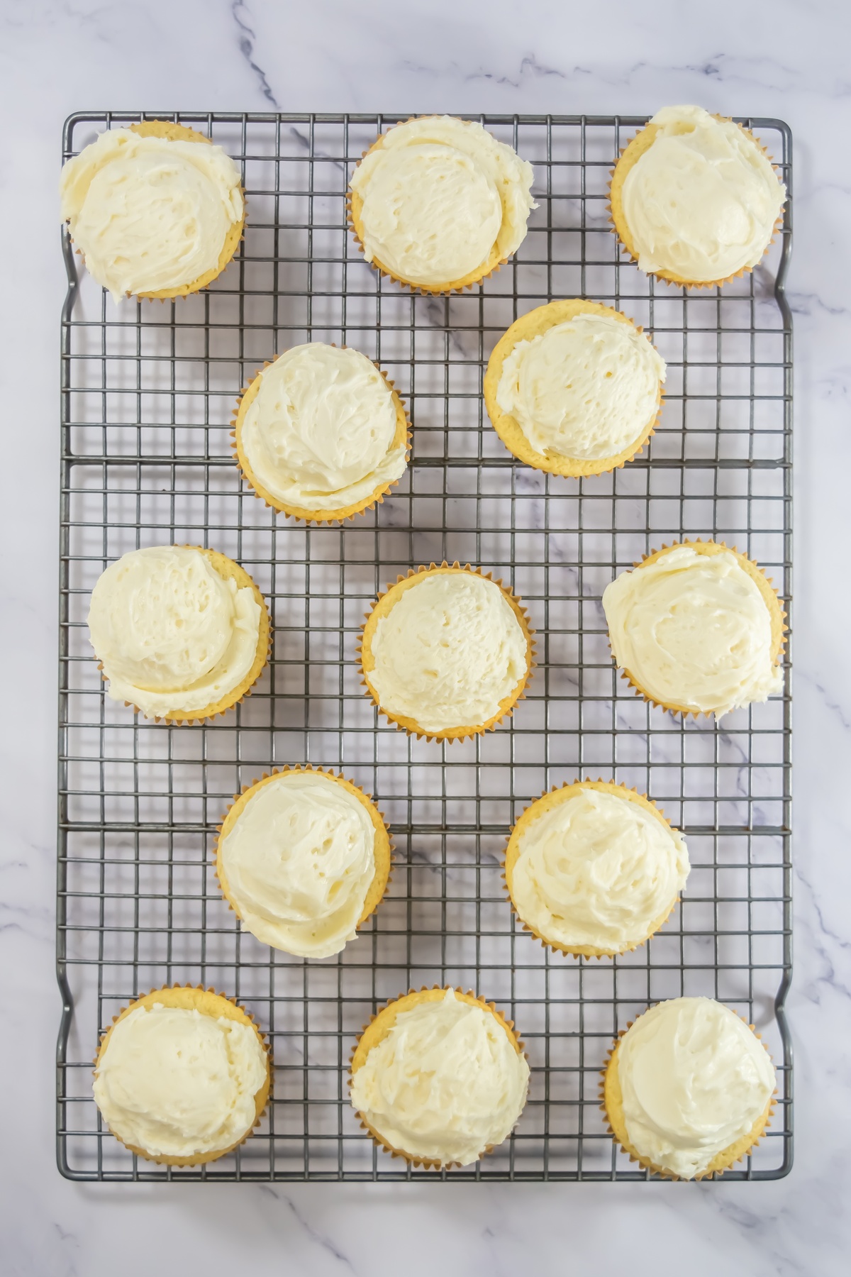 Cupcakes with frosting on a cooling rack.