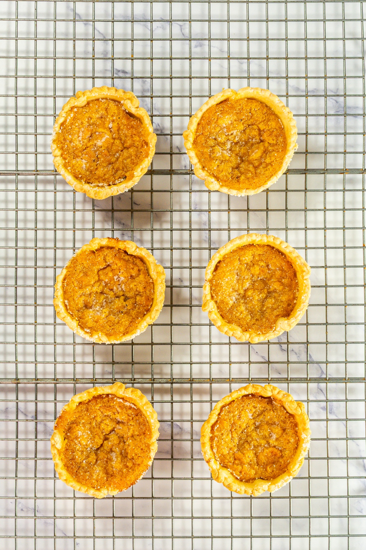 Mini sweet potato pies on a cooling rack.