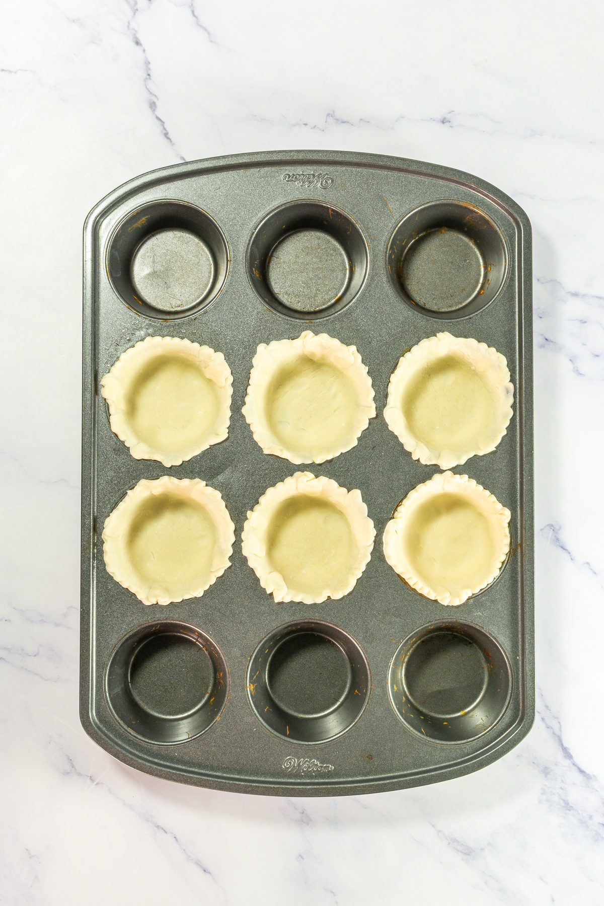 Pie crusts added into cupcake tin.