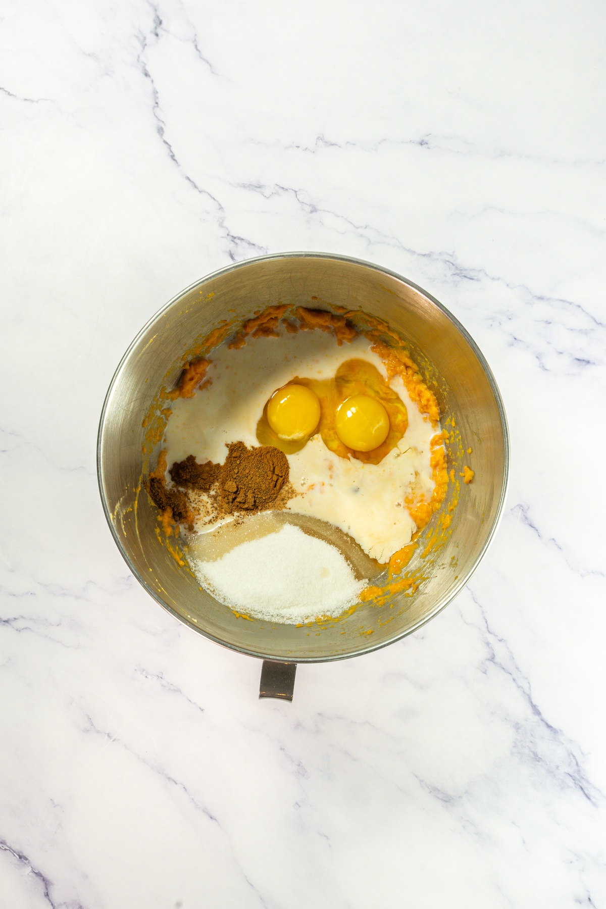 Eggs, spices added to sweet potatoes in a bowl.